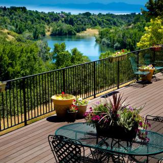 A scenic view from a wooden deck overlooking a lake surrounded by lush greenery.