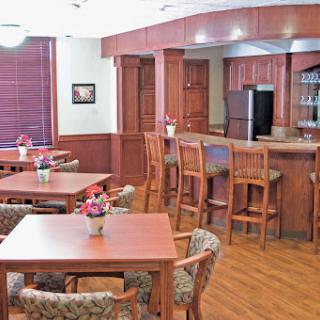 A cozy dining area featuring wooden tables and chairs, a bar counter, and decorative flowers.