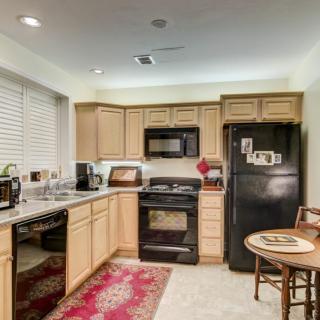 A cozy kitchen with light wood cabinets, black appliances, and a small dining area.