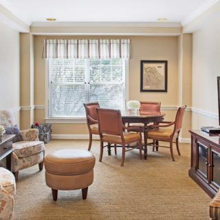 A cozy living room with a seating area and natural light streaming in through the window.