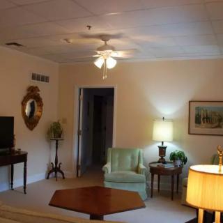 A cozy living room with traditional decor, featuring a television, lamps, and comfortable seating.