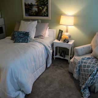 A cozy bedroom with soft lighting, featuring a comfortable bed and an inviting armchair.