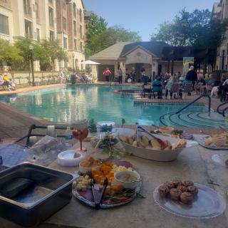 A poolside event with a variety of snacks and refreshments under the clear sky.