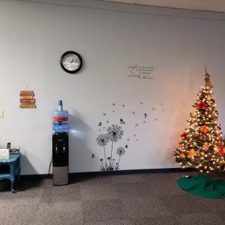 An office waiting area decorated with a Christmas tree and festive wall art.