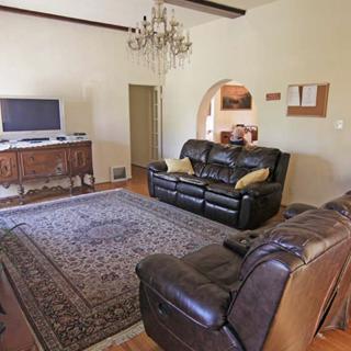 A cozy and spacious living room with leather sofas, a large rug, and a chandelier.