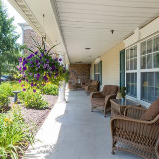 A peaceful porch with wicker chairs and hanging plants overlooks a garden.