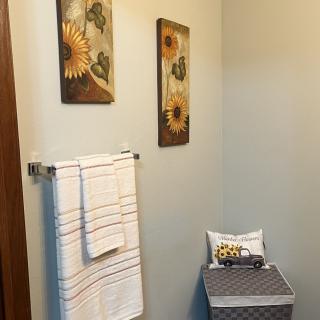 A well-decorated bathroom featuring sunflower artwork and neatly hung towels.
