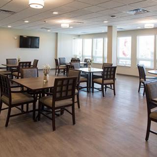 A modern dining area with several tables and chairs, illuminated by natural light.
