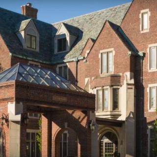 A grand, brick residential building with a classic architectural style and a sloped roof.