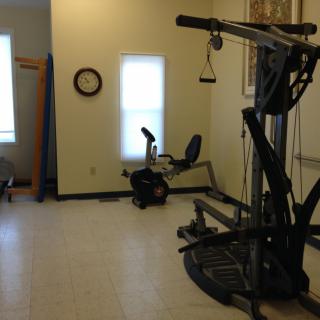 A small gym with various exercise equipment, including a weight machine and an exercise bike.