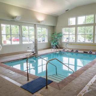A well-lit indoor swimming pool with large windows and a relaxing atmosphere.
