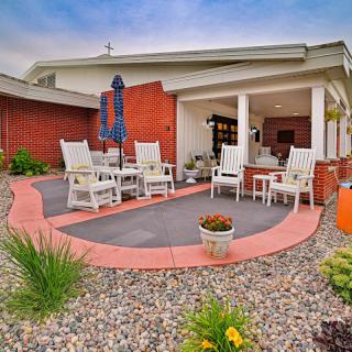 A cozy outdoor patio area featuring comfortable seating, a large umbrella, and beautiful landscaping.