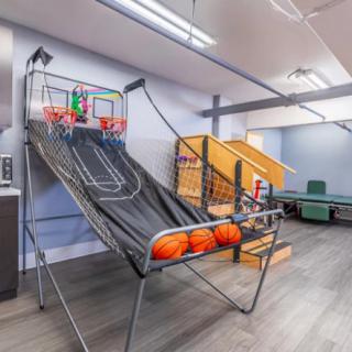 An indoor recreation room featuring an arcade basketball game setup.
