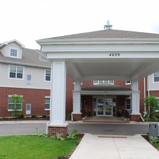 An entrance of a residential building with columns and a covered driveway.