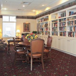A cozy library room with bookshelves, tables, and chairs.