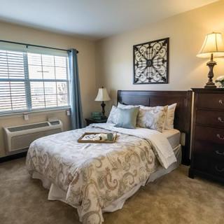 A cozy bedroom with a neatly made bed, a window letting in natural light, and stylish decor.