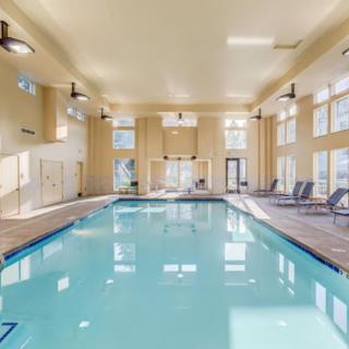 A spacious indoor swimming pool area with lounge chairs and large windows.