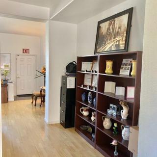 A cozy room featuring a bookshelf adorned with various vases and decor items, complemented by a painting above it.