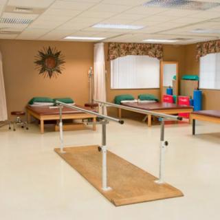 A rehabilitation room equipped with parallel bars and treatment tables for physical therapy.