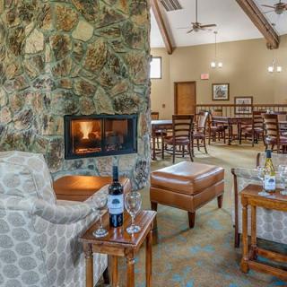 A cozy lounge area featuring a stone fireplace, comfortable seating, and a table set with wine.