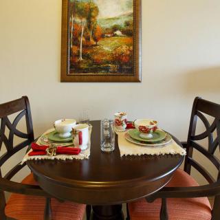 A cozy dining table for two with an elegant setting and a painting on the wall.
