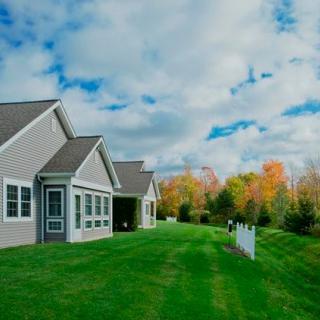 A suburban house with a well-maintained lawn surrounded by trees in autumn.