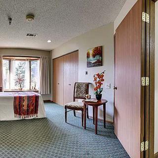 A well-decorated room with a table and chair by the window, featuring tasteful decor and carpeting.