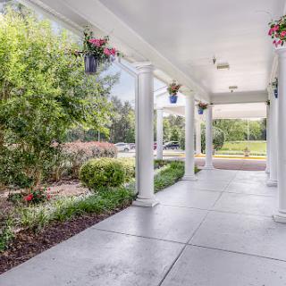A serene outdoor porch surrounded by lush greenery and decorative flower pots.