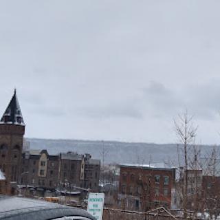 A snowy winter day in the city, with an overcast sky and distant mountains.
