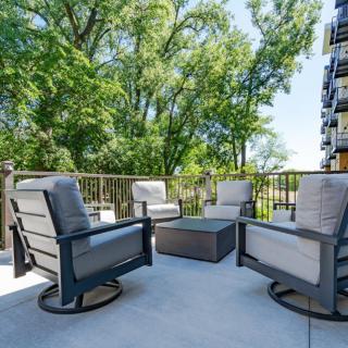 A cozy outdoor patio setup with cushioned chairs and a table on a deck surrounded by trees.