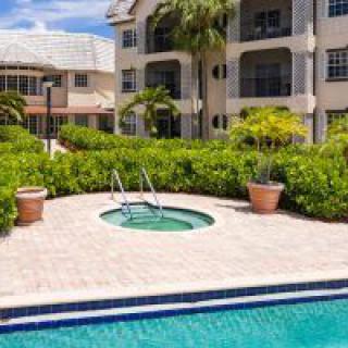 A beautiful resort setting with a swimming pool and jacuzzi surrounded by lush landscaping.