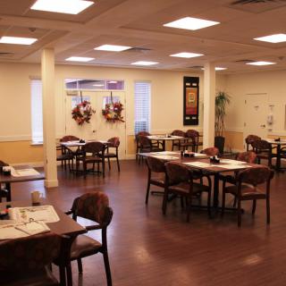 An empty restaurant dining area with neatly arranged tables and chairs, featuring a warm interior design.