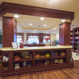 A cozy kitchen interior with wooden cabinets and a countertop, featuring well-lit shelves displaying various decor items.