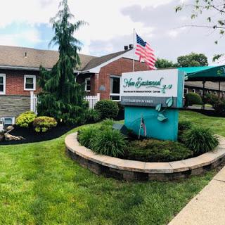 A welcoming view of a well-maintained building with lush landscaping and an American flag.