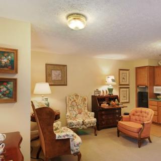 A cozy living room with traditional furniture and decor, featuring armchairs and warm lighting.