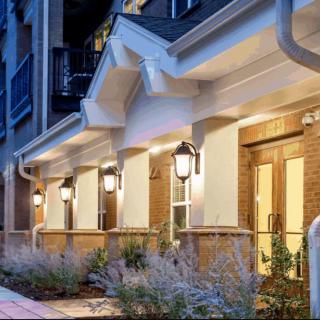 A well-lit residential building with multiple doorways in the evening.