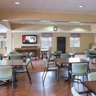 A spacious dining area with multiple tables, chairs, and a television mounted on the wall.
