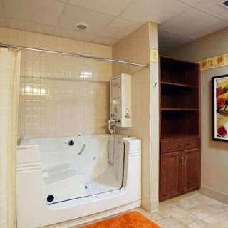 A modern bathroom featuring a walk-in tub with safety features, accompanied by shelving and minimalistic decor.