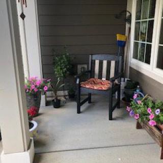 A cozy porch with a chair and vibrant potted plants.