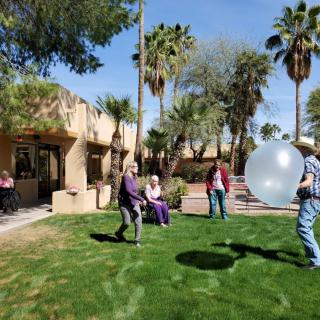 A group of people enjoying an outdoor activity with a large balloon on a sunny day.