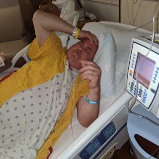 A patient resting in a hospital bed, appearing to be in discomfort.