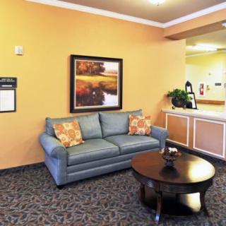 A cozy lobby area featuring a blue sofa and a round coffee table, complemented by artwork on the wall.