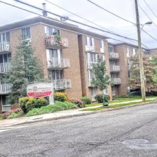 A view of a residential apartment building with greenery in the foreground.