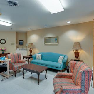 A cozy living room setup featuring a blue sofa, patterned chairs, and warm lighting.