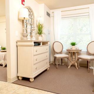 A cozy and elegantly decorated living space with light-colored furniture and greenery accents.