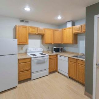 A modern kitchen with wooden cabinets and essential appliances including a refrigerator, stove, and microwave.