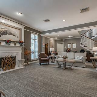 A spacious and elegantly designed living room featuring a fireplace, comfortable seating, and a modern staircase.