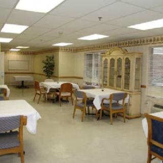 A neatly arranged dining area with several tables and chairs, featuring a cabinet along the wall.