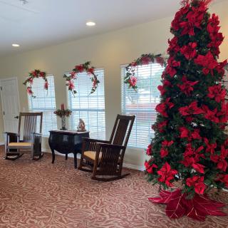 A cozy indoor setting with a beautifully decorated Christmas tree and rocking chairs by the window.