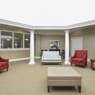 A spacious lobby area featuring comfortable seating with chairs and a sofa, complemented by decorative pillars.